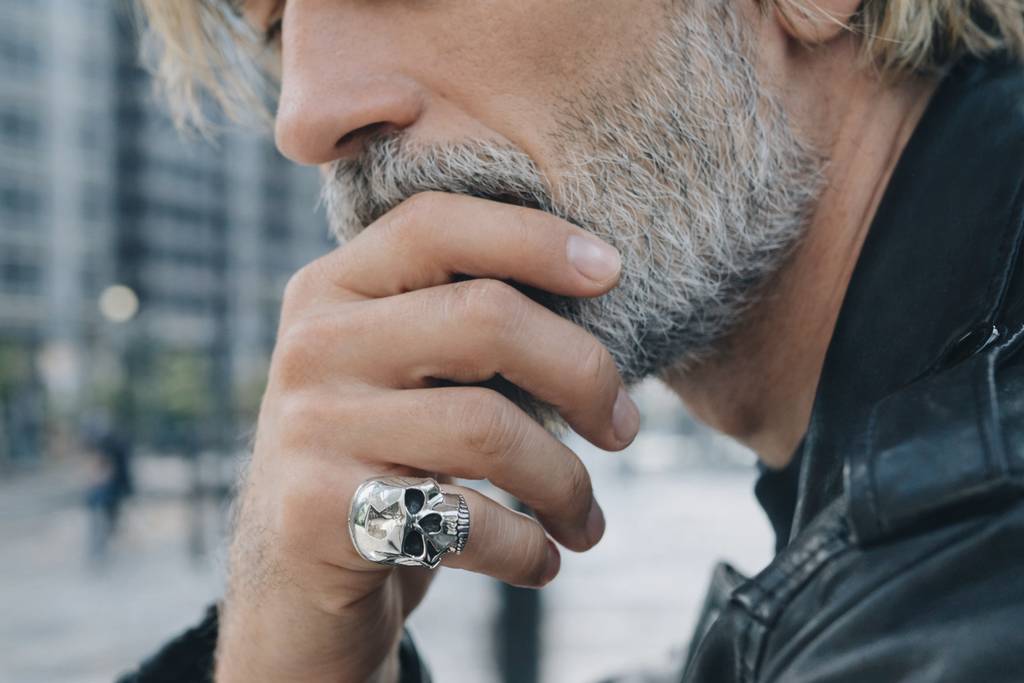 бородатый мужчина с кольцом в виде черепа на руке
